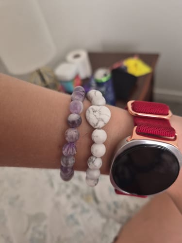 Customer's VIP Crystal Club beaded bracelets, one purple and one white with a heart, worn on a wrist next to a watch.