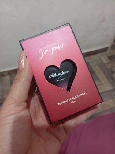 Customer's hand holding the rectangular box of Perfume Attracione Feminino, featuring a heart-shaped cutout.