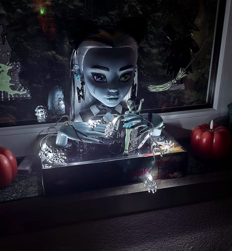 Customer's weiße Halloween Skelett-Hand LED Lichterkette drapiert um eine auffällige Figur vor einem Fenster.