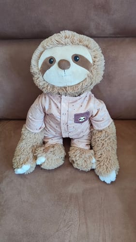 Klant's Luiaard Kleding Origineel Lotgenootje, een zachte knuffel in een lichtroze pyjama met een klein slakken-logo.