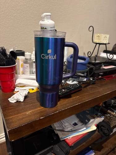 Customer's blue 40oz All-Day StrawSip Tumbler with a flavor cartridge on top, sitting on a cluttered wooden surface.