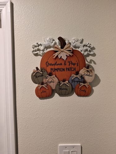 Customer's Grandma and Pap's Pumpkin Patch door hanger displayed on a plain wall above a light switch