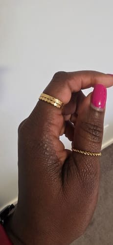 Reviewer's hand wearing three thin, gold-colored stacking rings on their fingers.