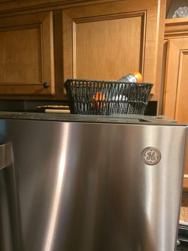 Reviewer's Adult Mask + Child Mask stored in a black woven basket sitting on top of a refrigerator.