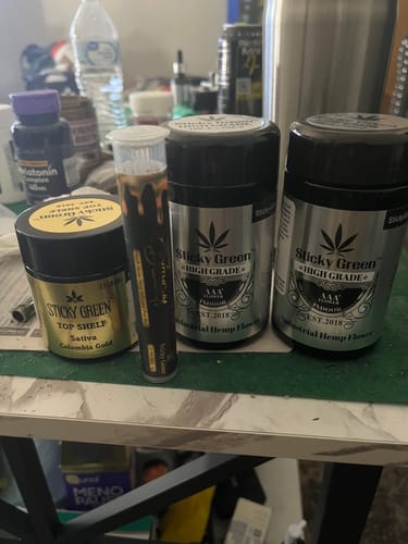 Customer's Colombia Gold Top Shelf flower gold jar alongside a pre-roll tube and two silver high grade jars.