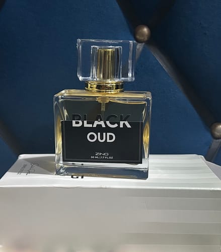 Customer's Black Oud perfume bottle with a golden cap and label, resting on a white box.