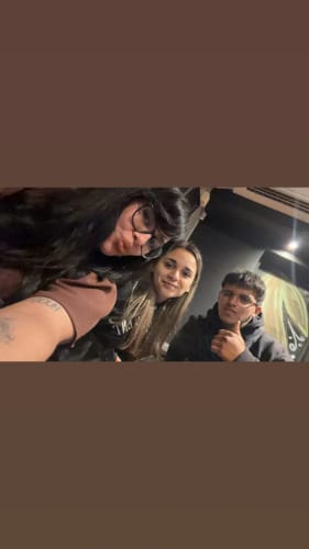 Customer's photo of three people, including one person showing a tattoo, in a casual setting.