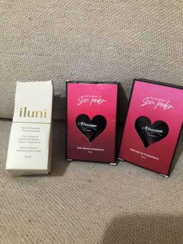 Customer's boxes of Perfume Attracione Sensual and a bottle of Iluni serum placed together on a textured surface.