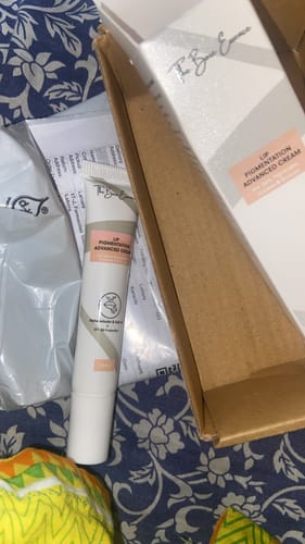 Customer's Advance Lip Pigmentation Cream tube and box shown on a patterned fabric surface.