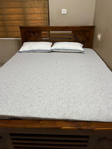 Customer's Flo Anti-Gravity Mattress with white pillows on a wooden bed frame in a bedroom.