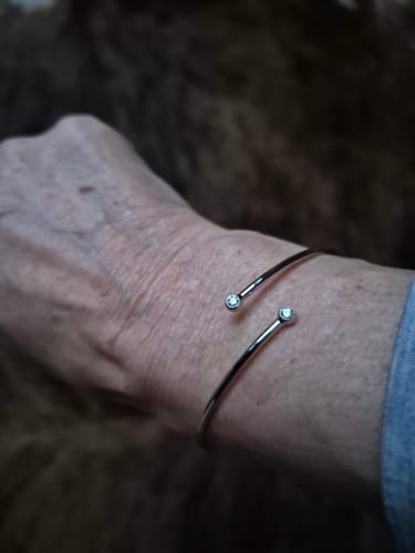 Customer's silver Rosia Bracelet worn on wrist, showing the open minimalist design with two small stones.