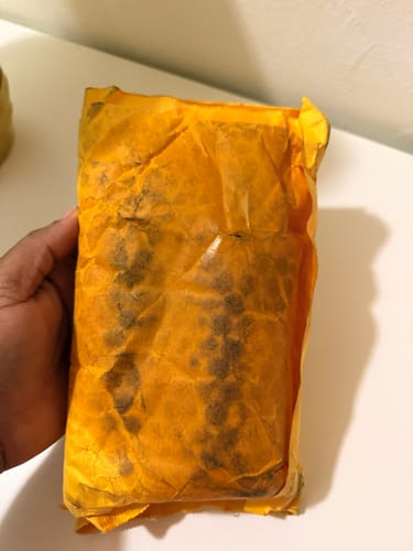 Customer's packaging for Brightening Body Oil, showing stained yellow bubble mailer after product leakage