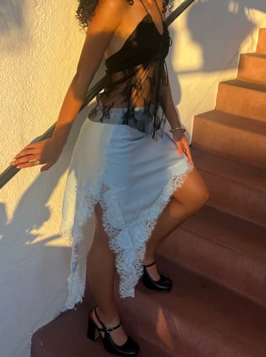 Reviewer wearing the light blue Asymmetrical Satin Lace Mini Skirt with lace hem detailing while standing on stairs