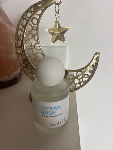 Customer's frosted glass Ocean Rush perfume bottle standing in front of a decorative gold crescent moon and star.