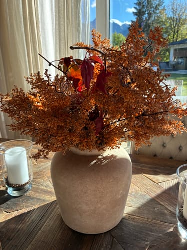 Customer's Herfst takken in een beige vaas op een houten tafel bij daglicht.