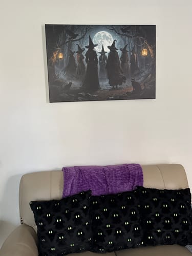 Customer's Coven of Witches wall art hanging on a white wall above a couch with purple and black ghost pillows.