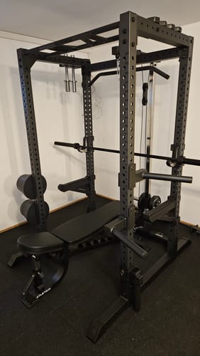 Customer's black R7 Cage power rack with an attached bench in a home gym setting.