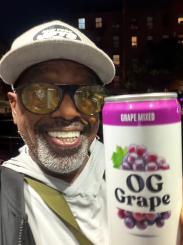 Customer smiling and holding an OG Grape infused soda can from the 100MG Infused Soda line.