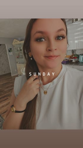 Customer wearing gold and freshwater pearl earrings, smiling for a selfie.