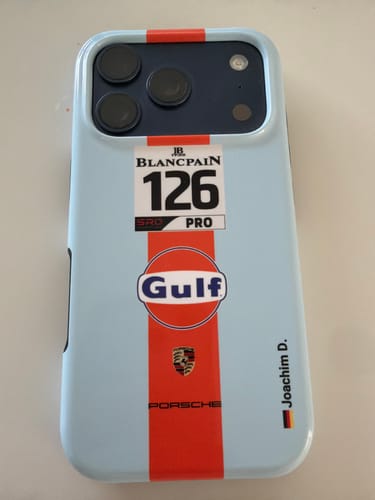 Kunden-iPhone mit hellblauer Gulf Porsche GT Hülle, die einen Rennstreifen, ein Blancpain-Logo und ein Porsche-Wappen zeigt.