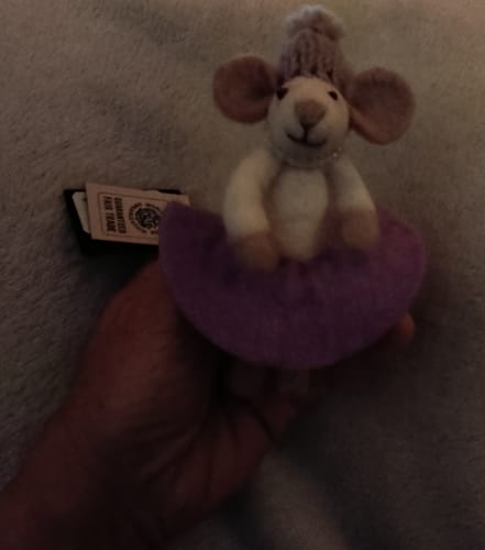 Customer's Gry & Sif Filzmaus held in hand, showing the beige mouse in a lila dress and matching knitted cap