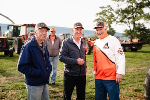 Customer's Premium Custom Leather Patch Hats worn by three people standing outdoors near farm machinery.