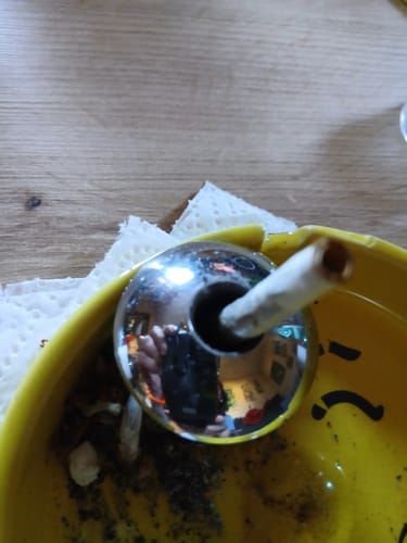 Kunden-Foto des THC-A 40% Hash Dry Static, das in einer gelben Schale in einer Zigarette platziert ist.