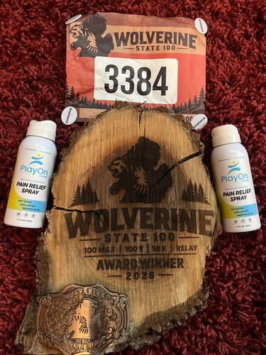 Customer's PlayOn Pain Relief Spray bottles next to a wooden race award and race bib.