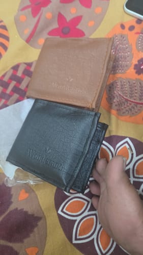 Customer's brown and black wallets, which are different from the requested Spiderman design, held in a hand.