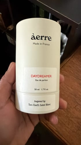 Customer's hand holding the cylindrical bottle of Aerre Daydreamer perfume.