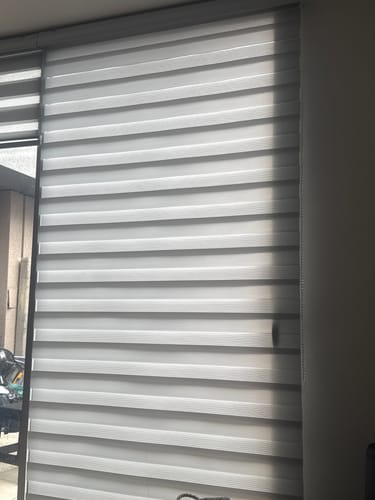 Customer's gray Cortina Roller Duo Zebra blind installed on a window, showing striped light and dark fabric patterns.