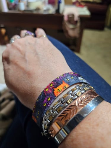 Customer's Cattitude bracelet with cat eye pattern worn on wrist with stacked metal bracelets