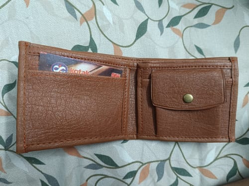 Customer's brown wallet, contrasting with the expected Spiderman design, resting on a patterned fabric surface.