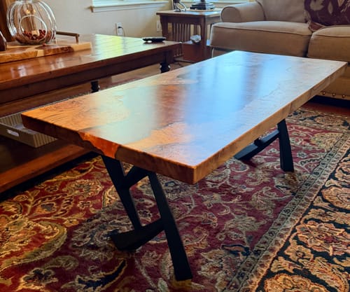 Customer's Draco metal bench legs supporting a beautiful live-edge wooden coffee table in a living room.