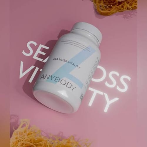 Customer's Anybody Sea Moss Vitality supplement bottle on a pink background with dried sea moss.