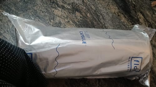 Customer's vacuum-packed Flo Anti-Gravity Mattress in white Sleep Capsule packaging delivered at home