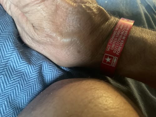 Customer's red Honor Our Fallen Heroes Memorial Bracelet worn on a person's wrist.
