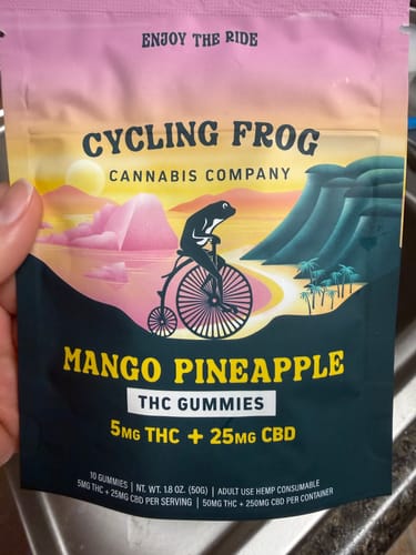 Customer's hand holding a colorful bag of Cycling Frog Mango Pineapple gummies