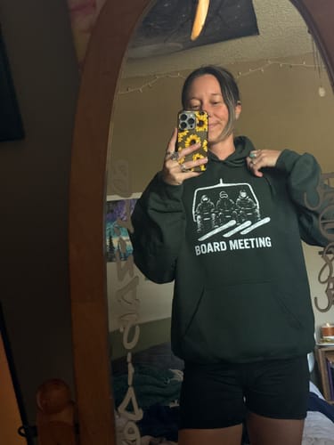 Customer wearing the dark green Snowboard Board Meeting hoodie in a mirror selfie