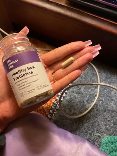 Reviewer's hand holding a Healthy Box Probiotics bottle and a single capsule.