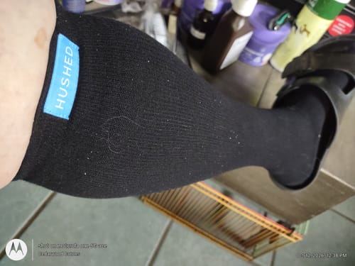 Customer's black Eucalyptus Lyocell Compression Socks on leg, showing the Hushed brand label.