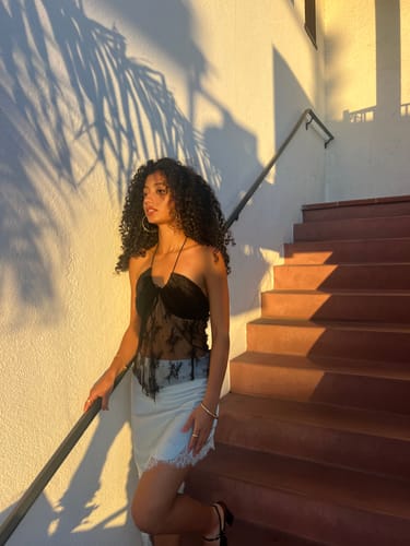 Customer's flattering black bandeau tank top worn on a staircase in golden hour light.