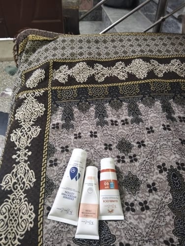 Customer's three tubes from the 24 Hour Glow Pack resting on a patterned fabric surface.