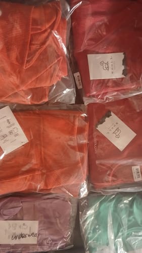 Customer's Mystery Bag items: multiple folded pieces of apparel in plastic packaging, including red, purple, and green.