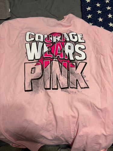 Reviewer's light pink Courage Wears Pink tee with a dark pink breast cancer awareness ribbon and bold graphic print.