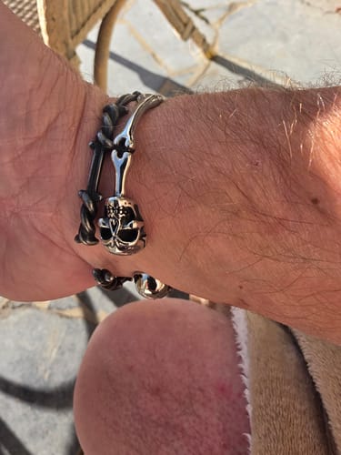 Customer's SKULLED silver-toned stainless steel bracelet on wrist, featuring a detailed skull design.