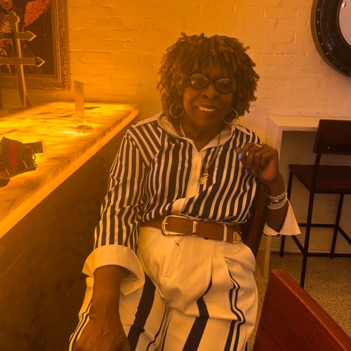 Customer's striped blazer worn by a person, seated in a dimly lit room.
