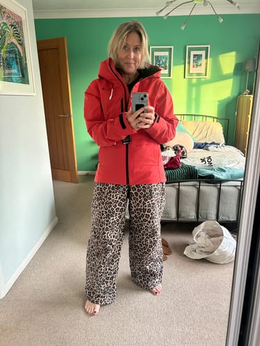 Customer's Women's Pink Leopard Recycled Minimalist Insulated Snow Pants worn by a person in a home setting.