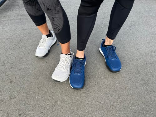 Customer's pair of white and pair of blue CUURT Muuv wide toe box court shoes worn by two people on concrete