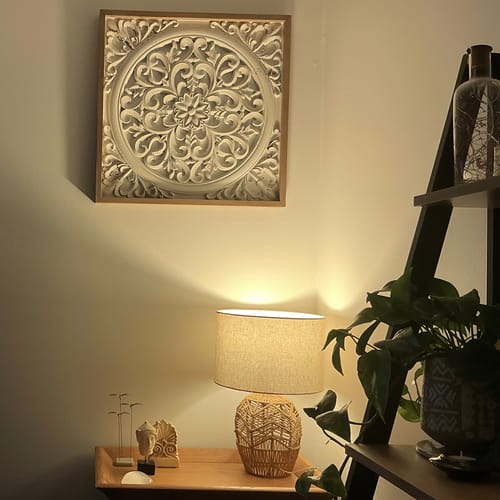 Customer's Henry Carved Mandala Wall Art mounted on a wall above a lamp, showing its intricate distressed white pattern.